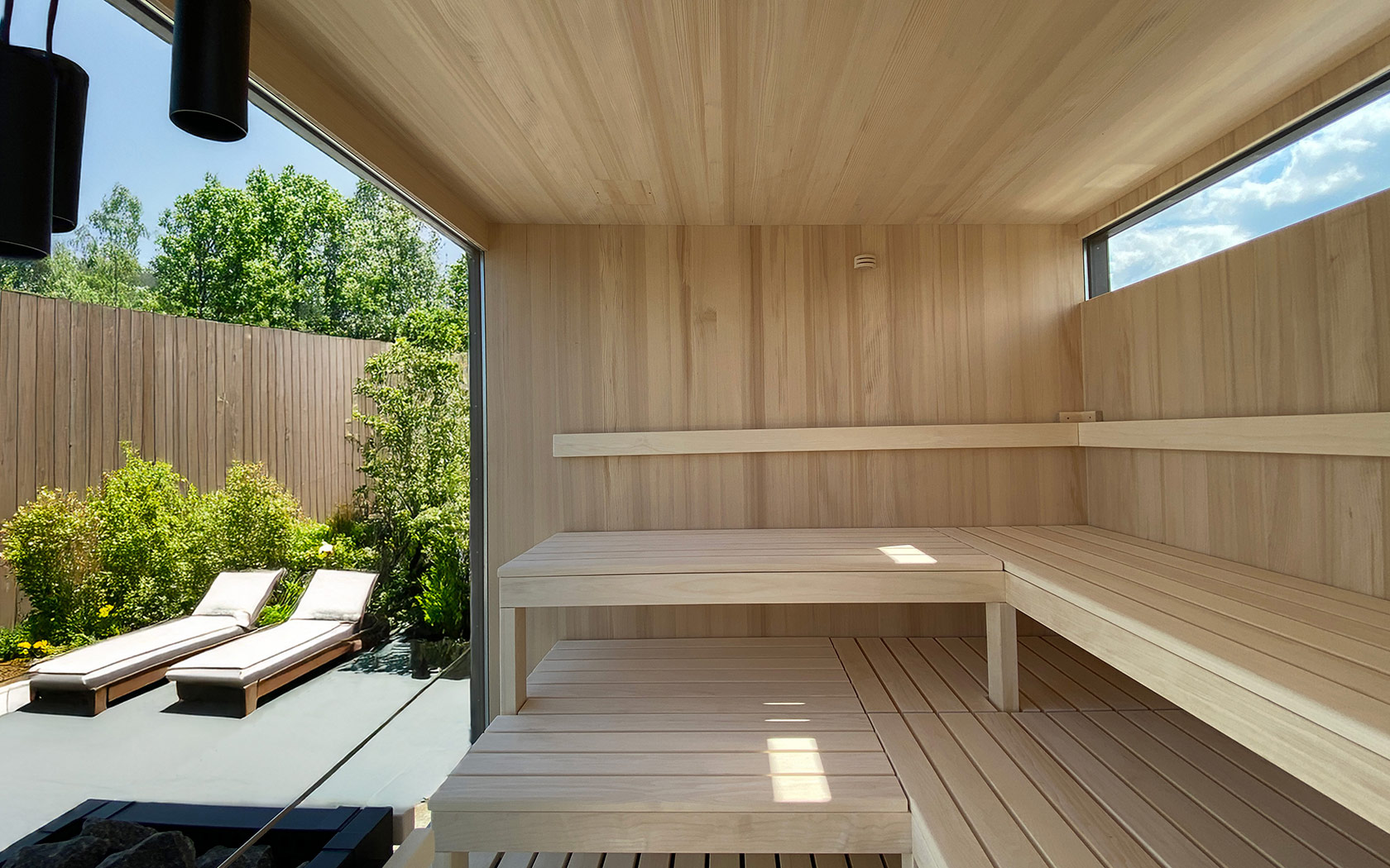 Innenansicht einer Sauna mit Sitzbank und Glaswand mit Blick in den Garten